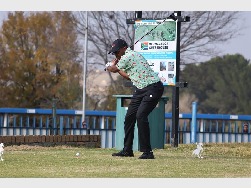 a man wearing a green shirt tees off in golf