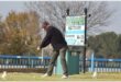 a man wearing a black shirt tees off in golf