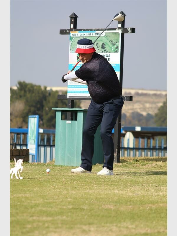 a man wearing a black shirt tees off in golf