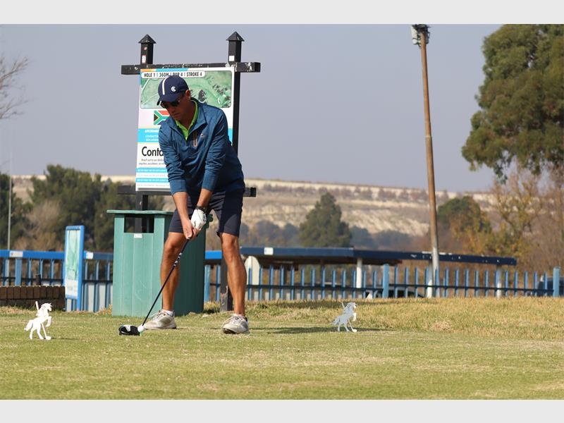 a man wearing a black shirt tees off in golf