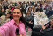 a woman in pink takes a selfie with many women at a ladies tea in the background