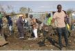 people clean up the area around shacks