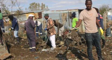 people clean up the area around shacks