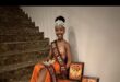 girl in orange dress wearing a crown and holding up 2 certificates