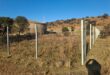 a grassland and hill with fence poles in the foreground