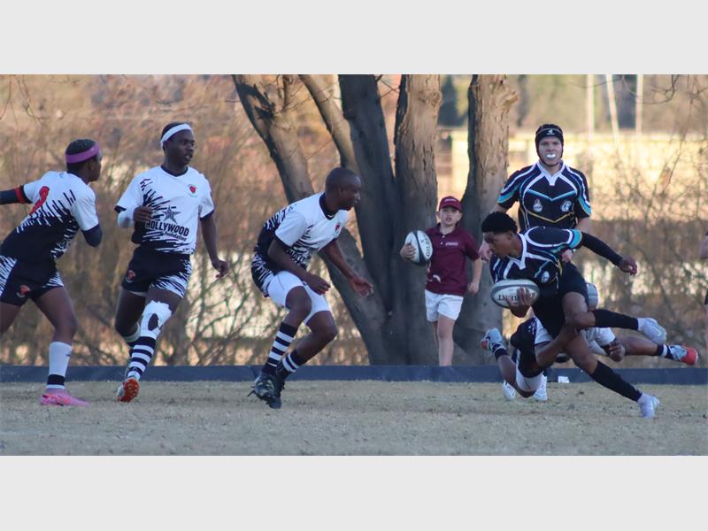 a rugby match between players in black and blue and a team in white and black.
