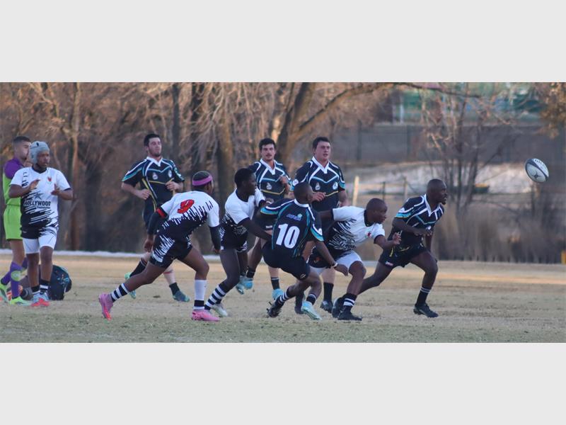 a rugby match between players in black and blue and a team in white and black.