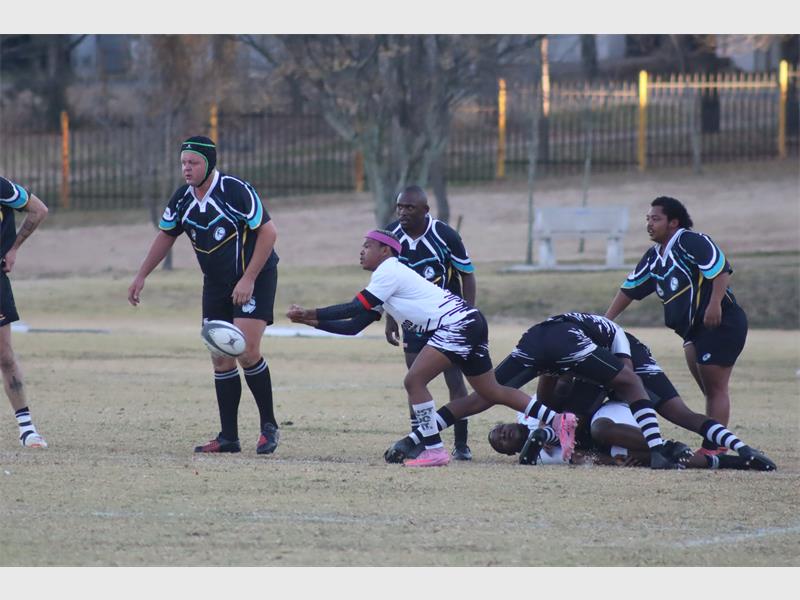 a rugby match between players in black and blue and a team in white and black.