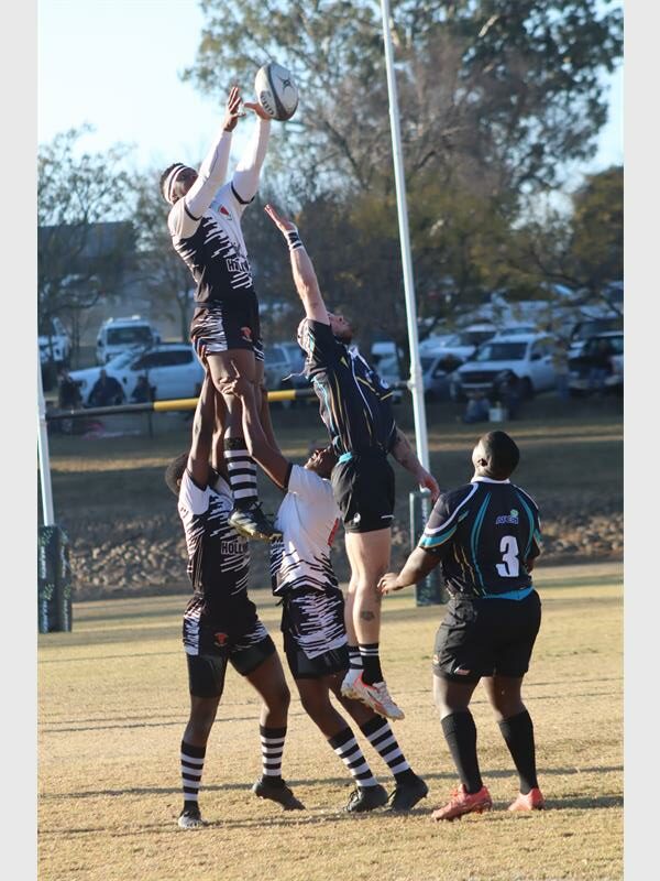 a rugby match between players in black and blue and a team in white and black.