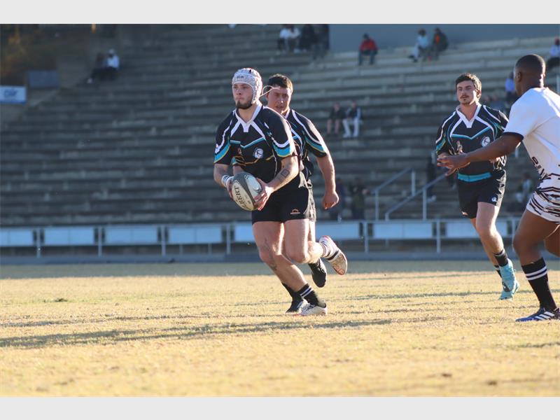 a rugby match between players in black and blue and a team in white and black.