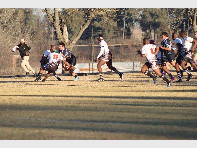a rugby match between players in black and blue and a team in white and black.