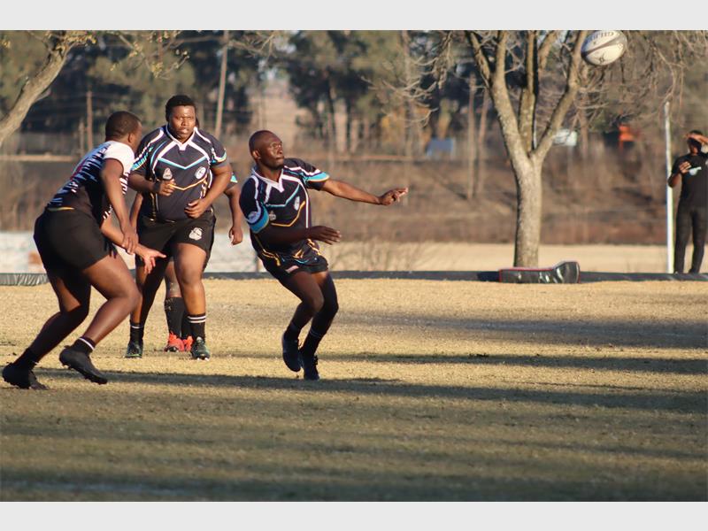a rugby match between players in black and blue and a team in white and black.