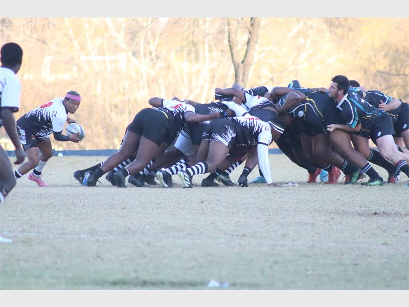 a rugby match between players in black and blue and a team in white and black.