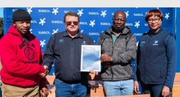 four people with a certificate and school desks