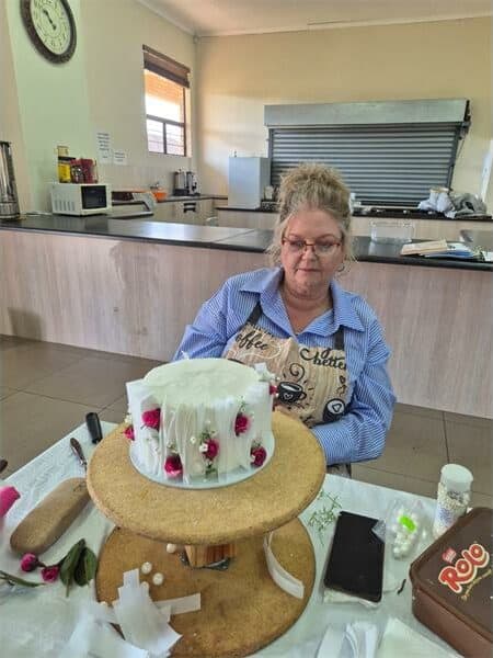 a woman in a stiped shirt decorates a cake