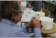 a woman in a stiped shirt decorates a cake