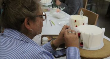 a woman in a stiped shirt decorates a cake