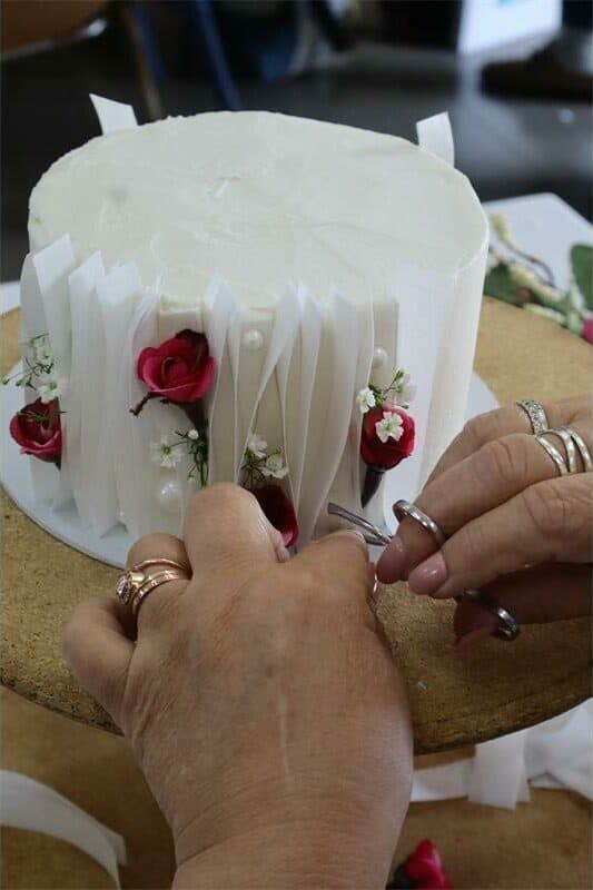 a woman in a stiped shirt decorates a cake