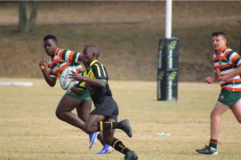 a boy in black and yellow rugby jersey runs at full speed