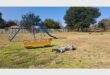 a person sleeping on the grass in a play area for children