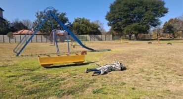 a person sleeping on the grass in a play area for children