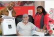 a blood donor is flanked by two employees of the blood bank