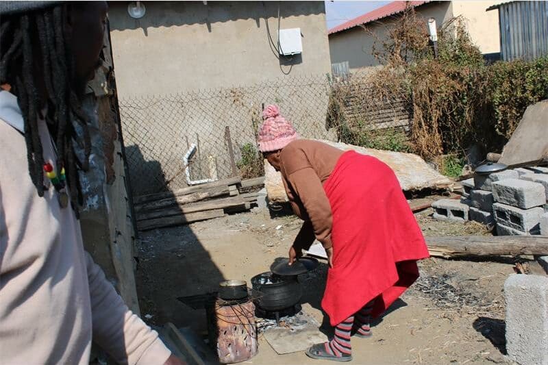 woman cooks over an open fire