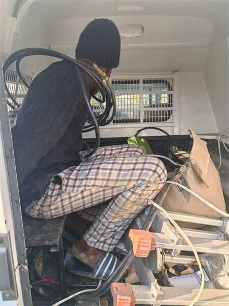 a man with electricity cables around him sits in the back of a police van