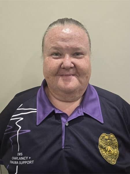 elderly woman in a navy and purple chaplaincy shirt