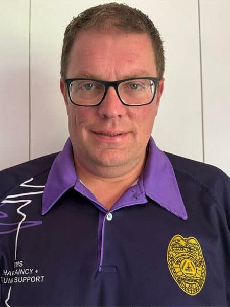 man with spectacles in a navy and purple chaplaincy shirt