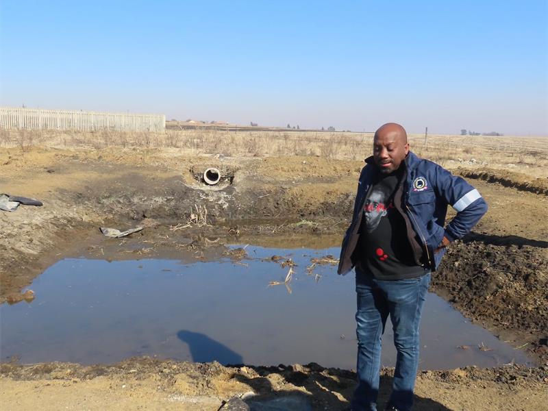 a man in a municipal overall stands next to a sewer dam