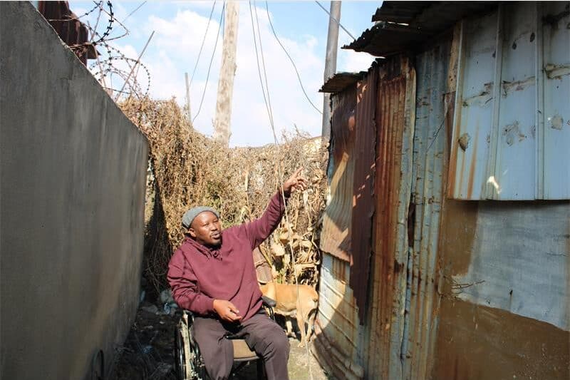 man in a wheelchair in front of a shack