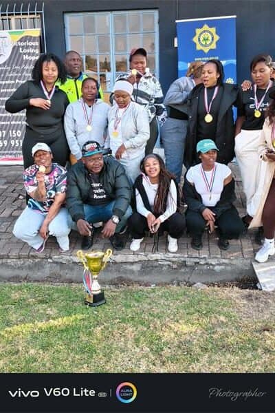 A group of people with a trophy on the lawn in front of them