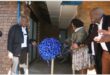 three people cutting a blue ribbon