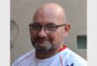 man with bold head, spectacles and a rugby shirt