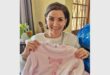 a woman holds up a set of pajamas for a girl