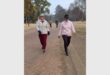 two women walking on a dirt road