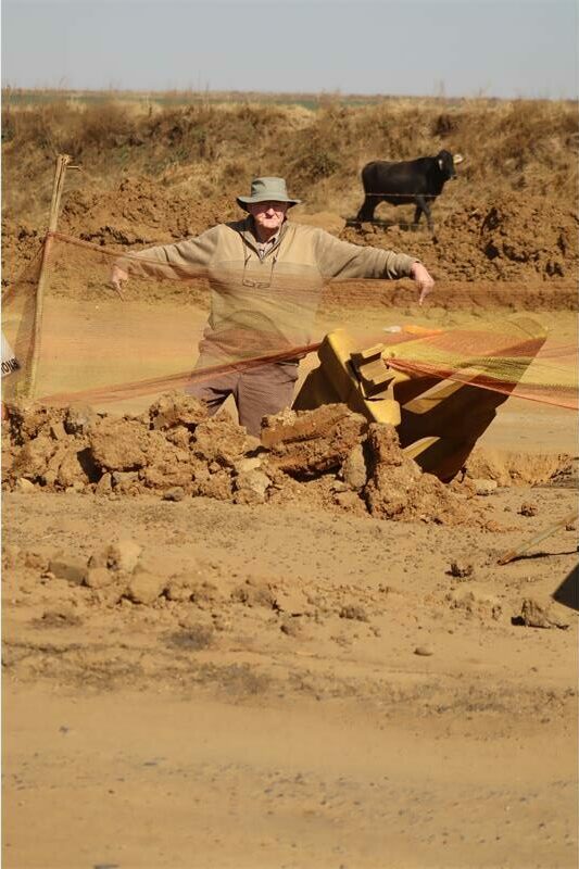 man standing a huge hole in the road