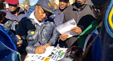 a police woman signs memorandum surrounded by people