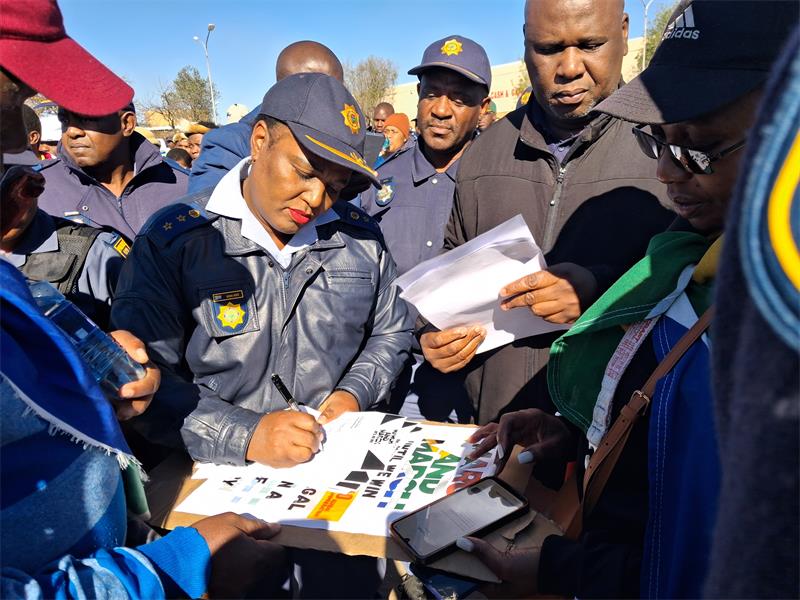 a police woman signs memorandum surrounded by people