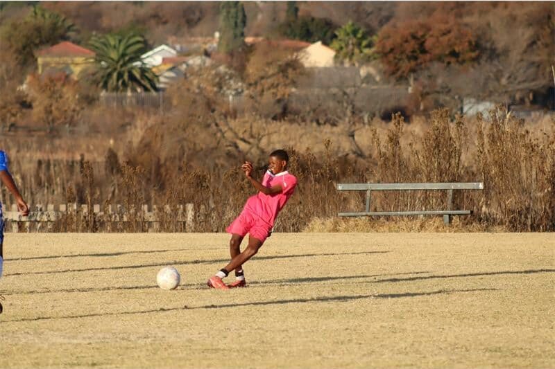 soccer players in blue and one in pink vie for the ball