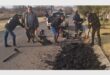 people work to fill up potholes