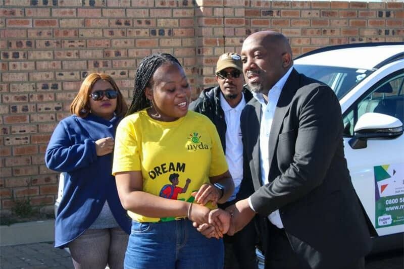 woman in a yellow t shirt is shaking hands with a man in a suit
