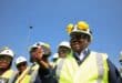 man in a reflector jacket and hard hat inspects a lump of coal.
