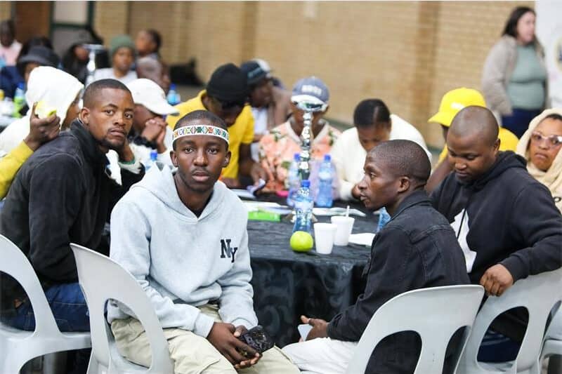 people sit around tables and listen to a speaker