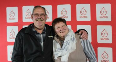 a man and a woman hugging in front of a blood bank back drop