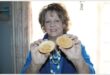 A woman holds up two bars of honey soap