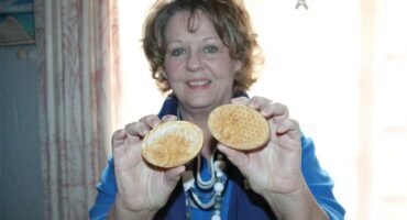 A woman holds up two bars of honey soap