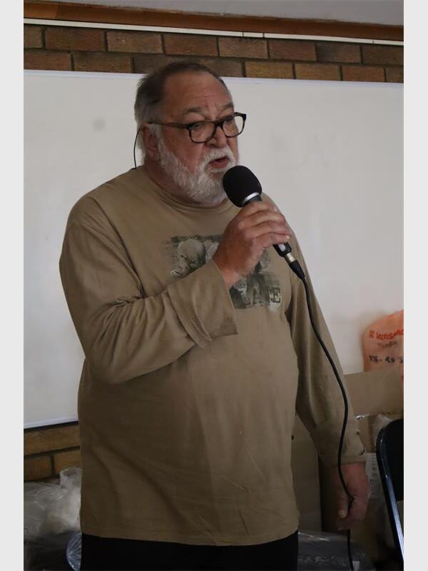 A man with a khaki T shirt and a beard sings oer a microphone