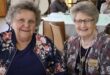 two elderly women sit at a table